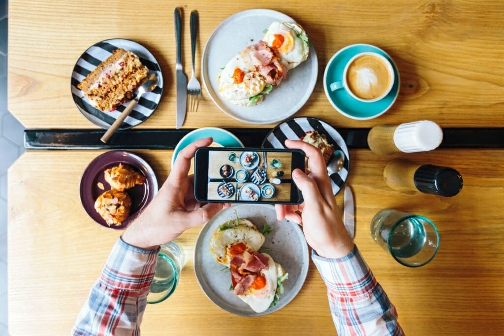 personal perspective view of man photographing his brunch in cafe with smartphone