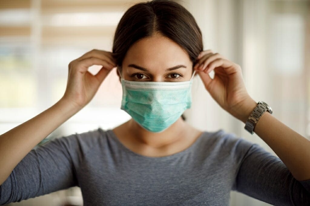 Portrait of young woman putting on a protective mask